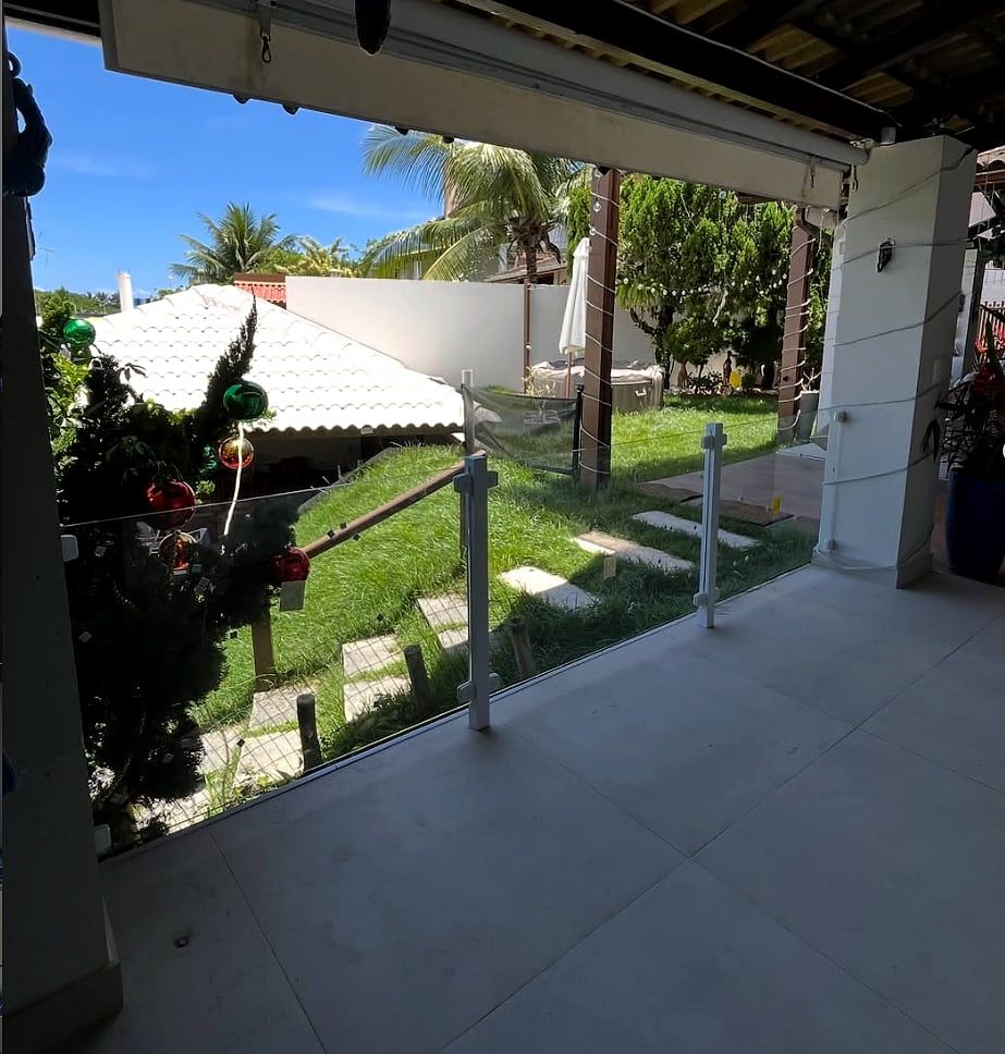 A mesma varanda depois: guarda-corpo de vidro instalado nos montantes, com vista para o jardim